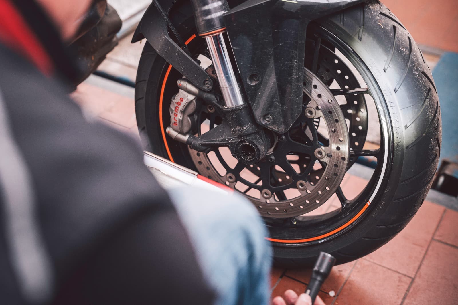 Prüfung von Bremsscheibe, Bremssattel und Vorderreifen an einem Motorrad